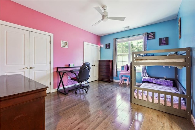 bedroom with ceiling fan, wood finished floors, two closets, and baseboards