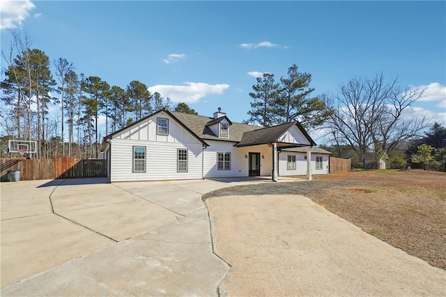 view of front of house featuring roof with shingles, covered porch, board and batten siding, fence, and driveway