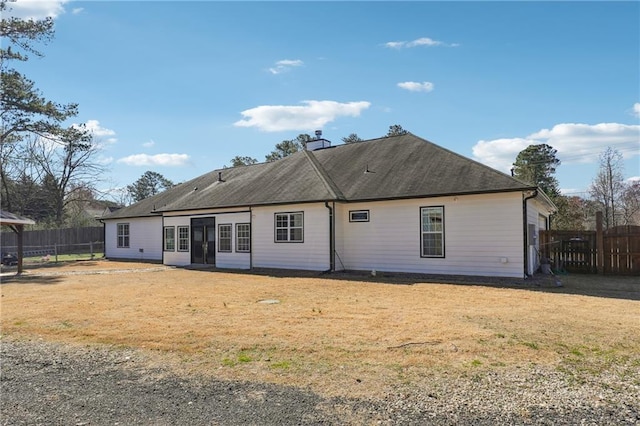 rear view of property featuring a chimney, fence, and a yard