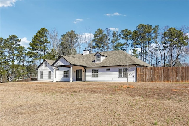 view of front of home with a chimney, fence, and a front yard