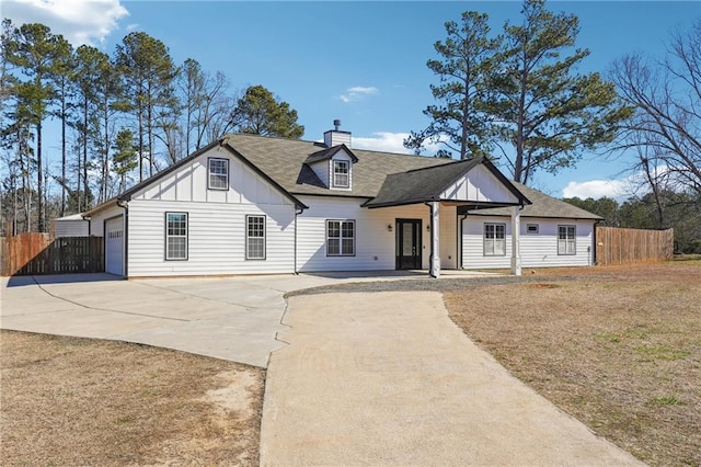 view of front of home featuring driveway, a garage, a chimney, fence, and board and batten siding