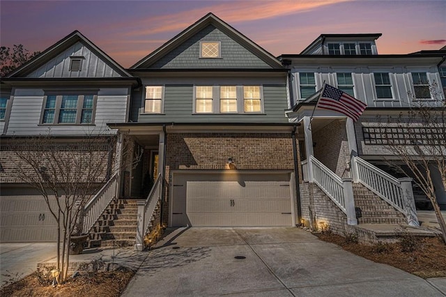 view of front facade with stairs, concrete driveway, brick siding, and a garage