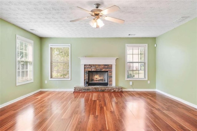 unfurnished living room featuring wood-type flooring, a textured ceiling, a fireplace, and ceiling fan