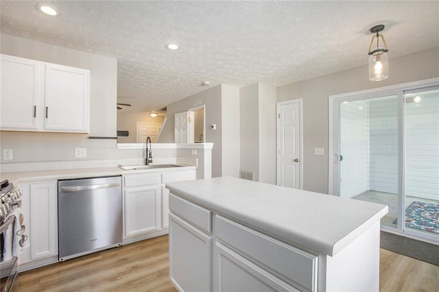 kitchen featuring white cabinets, decorative light fixtures, stainless steel appliances, light countertops, and a sink