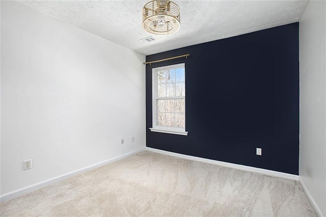 carpeted empty room featuring visible vents, baseboards, and a textured ceiling