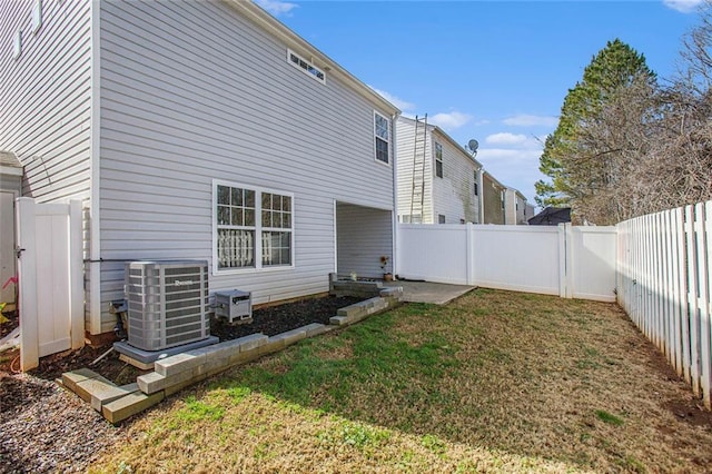 rear view of property featuring a fenced backyard, a lawn, and central air condition unit