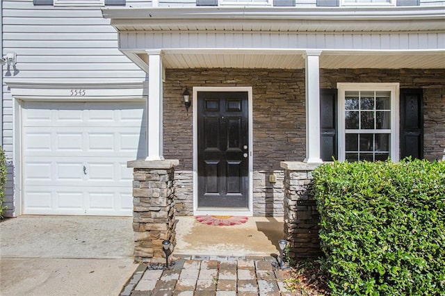 doorway to property with a garage and stone siding