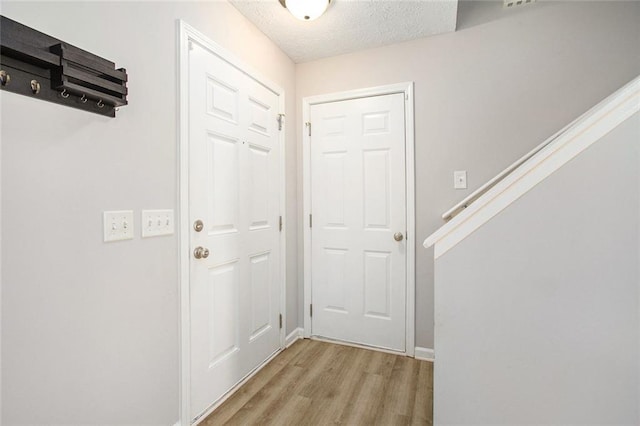 doorway featuring light wood-type flooring and a textured ceiling