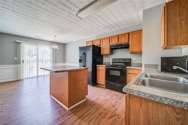 kitchen featuring sink, black appliances, light hardwood / wood-style floors, a kitchen island, and decorative light fixtures