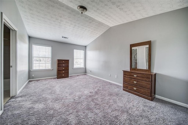 unfurnished bedroom with lofted ceiling, a textured ceiling, and carpet flooring