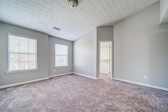 carpeted empty room featuring lofted ceiling and a textured ceiling