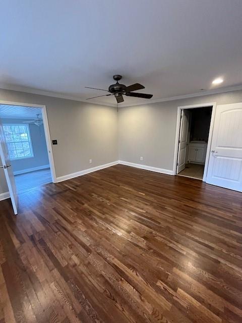 empty room with ornamental molding, dark wood finished floors, baseboards, and ceiling fan