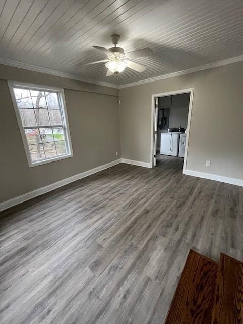 spare room with ornamental molding, washing machine and dryer, dark wood-type flooring, ceiling fan, and baseboards