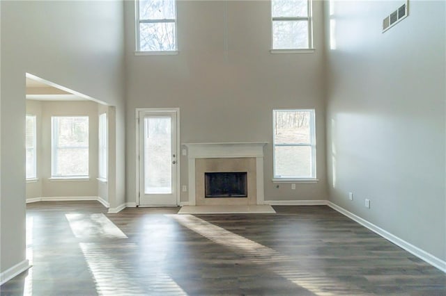 unfurnished living room with a wealth of natural light, a towering ceiling, and dark hardwood / wood-style floors