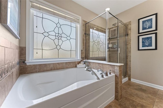 bathroom with plenty of natural light, a bath, a stall shower, and baseboards