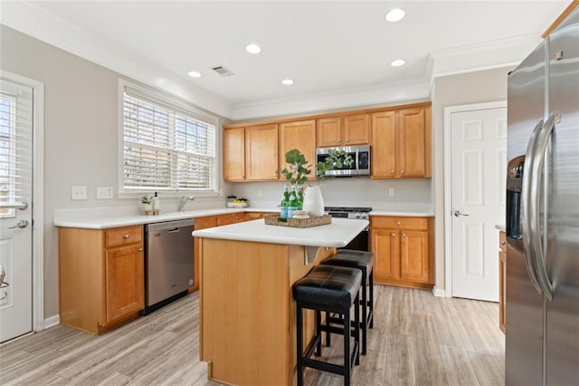 kitchen featuring appliances with stainless steel finishes, ornamental molding, and light countertops