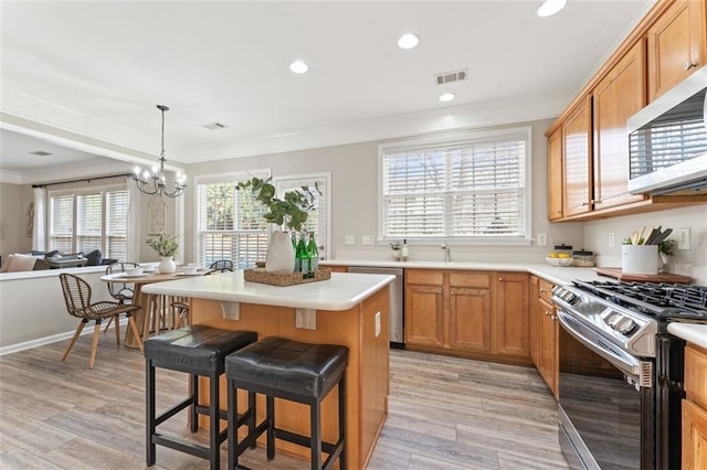 kitchen featuring visible vents, a center island, a kitchen bar, ornamental molding, and stainless steel appliances