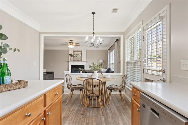 dining space with visible vents, ornamental molding, light wood-style floors, a fireplace, and baseboards