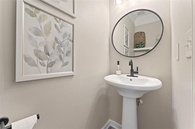 bathroom featuring crown molding and a sink