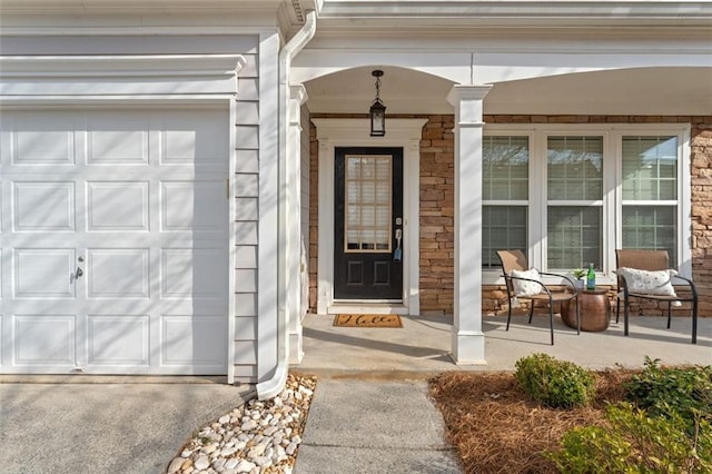 property entrance with stone siding, covered porch, and driveway