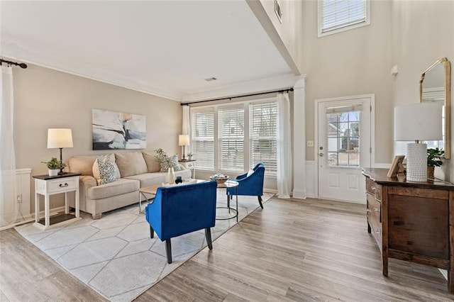 living area featuring wainscoting, light wood-type flooring, and ornamental molding