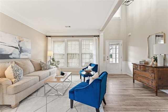 living area featuring visible vents, light wood-style floors, wainscoting, and ornamental molding