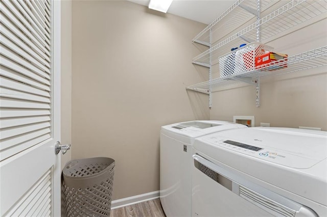 washroom with washer and dryer, baseboards, wood finished floors, and laundry area