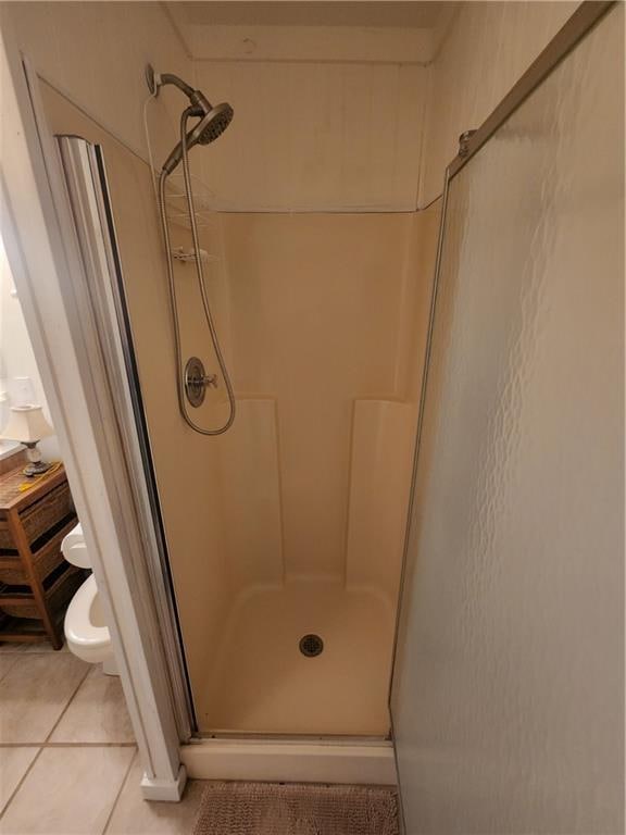 bathroom with tile flooring, an enclosed shower, and toilet