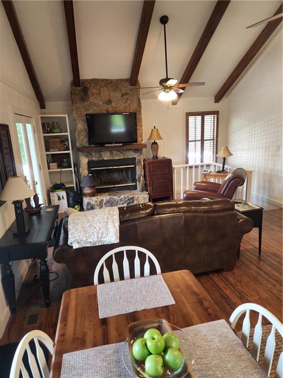 living room featuring vaulted ceiling with beams, dark hardwood / wood-style flooring, ceiling fan, and a fireplace