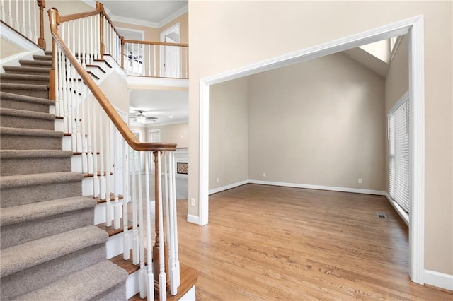 4957 Day Lily Way NW, Acworth, GA 30102 - stairway featuring crown molding, wood finished floors, a ceiling fan, baseboards, and a high ceiling