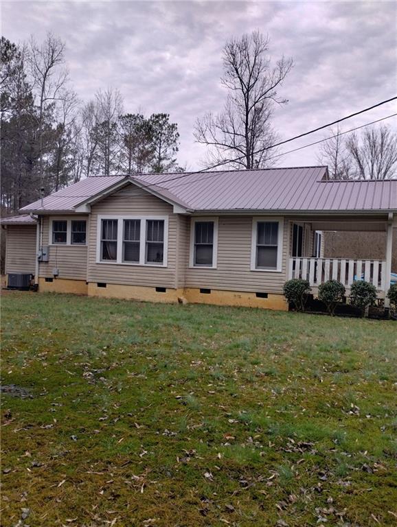 view of front of house featuring crawl space, metal roof, and a front yard