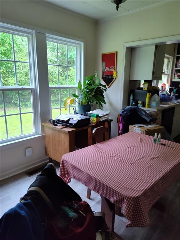 dining area with light wood-style flooring, baseboards, and crown molding