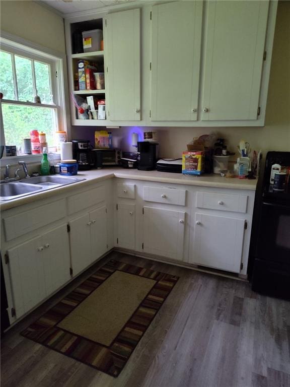 kitchen with stove, a sink, white cabinets, and light countertops