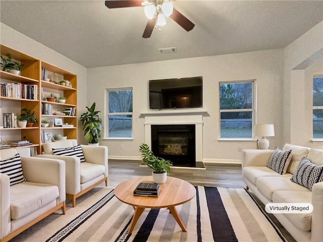 living room featuring hardwood / wood-style floors, built in shelves, and ceiling fan