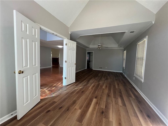 spare room with dark wood-style flooring, lofted ceiling, a raised ceiling, ceiling fan, and baseboards