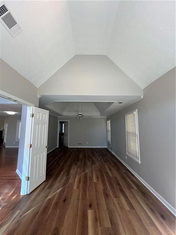 unfurnished living room featuring lofted ceiling, visible vents, baseboards, and wood finished floors