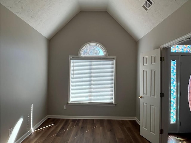 foyer entrance with lofted ceiling, wood finished floors, visible vents, and baseboards