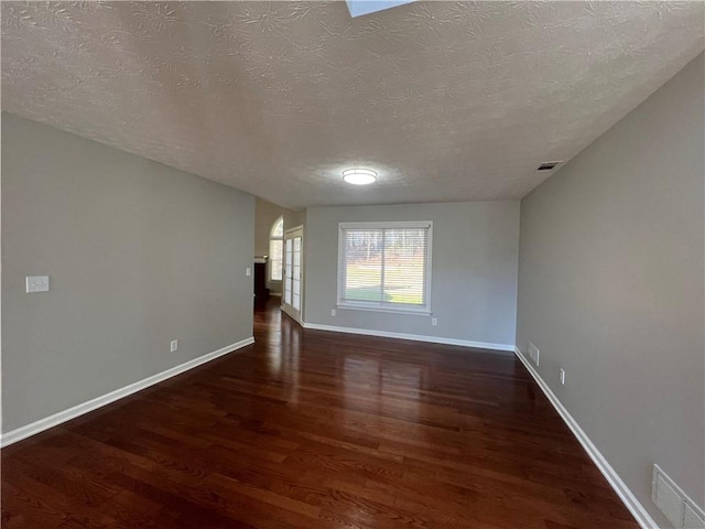 unfurnished room with visible vents, a textured ceiling, baseboards, and wood finished floors