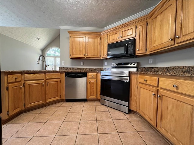 kitchen with light tile patterned floors, lofted ceiling, appliances with stainless steel finishes, a textured ceiling, and a sink