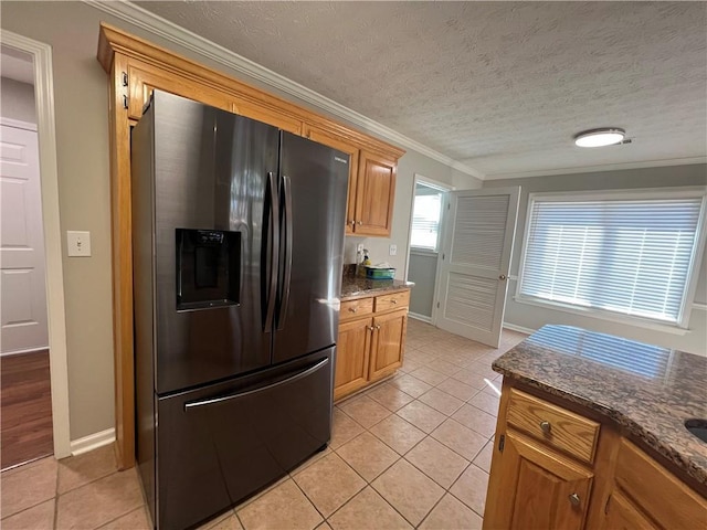 kitchen featuring light tile patterned floors, dark stone countertops, fridge with ice dispenser, crown molding, and a textured ceiling