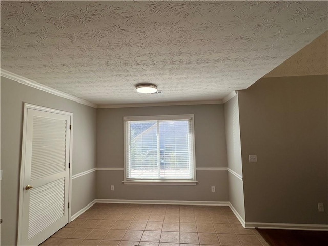 spare room with light tile patterned floors, baseboards, and a textured ceiling