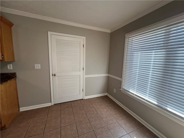 unfurnished dining area with a healthy amount of sunlight, baseboards, ornamental molding, and tile patterned floors