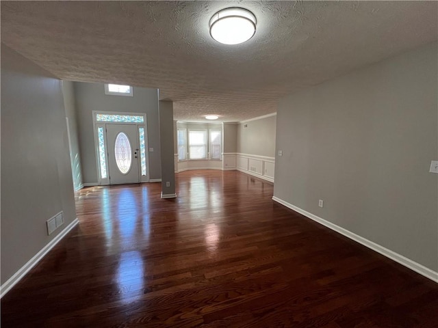 foyer featuring a textured ceiling, dark wood finished floors, visible vents, and baseboards