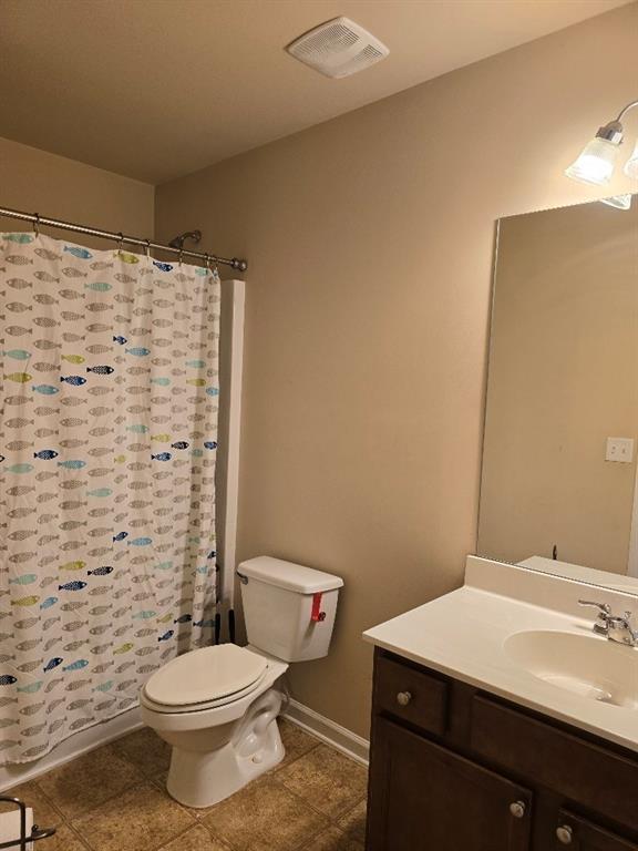 bathroom with tile patterned flooring, walk in shower, vanity, and toilet