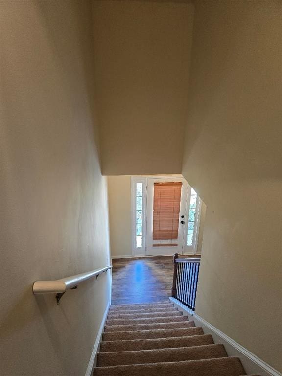 stairway featuring a towering ceiling and hardwood / wood-style floors