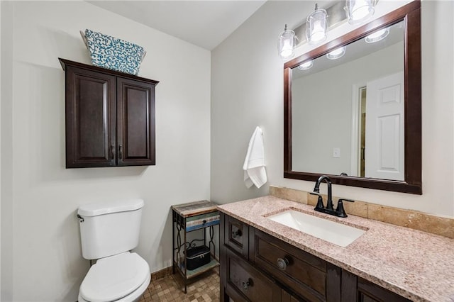 bathroom featuring toilet, vanity, and baseboards