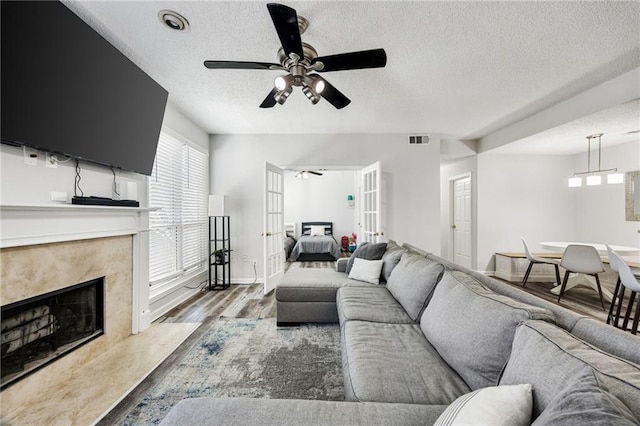 living room with visible vents, a fireplace, wood finished floors, a textured ceiling, and a ceiling fan