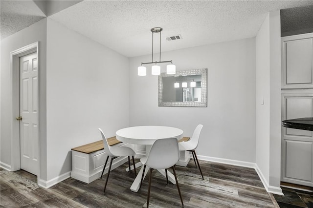 dining space featuring visible vents, dark wood-style flooring, and baseboards