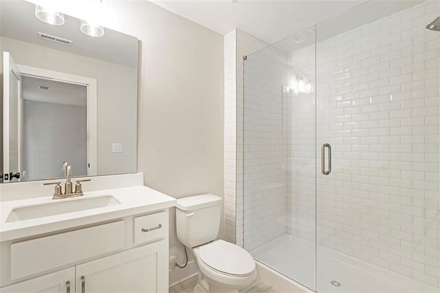 bathroom featuring vanity, toilet, and a shower with shower door