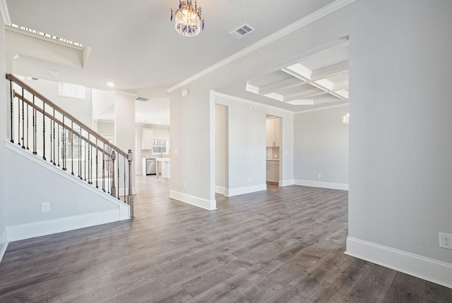 empty room with coffered ceiling, wood finished floors, visible vents, and baseboards